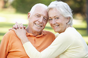 The image shows an elderly couple, a man and a woman, embracing each other in a warm and affectionate manner.
